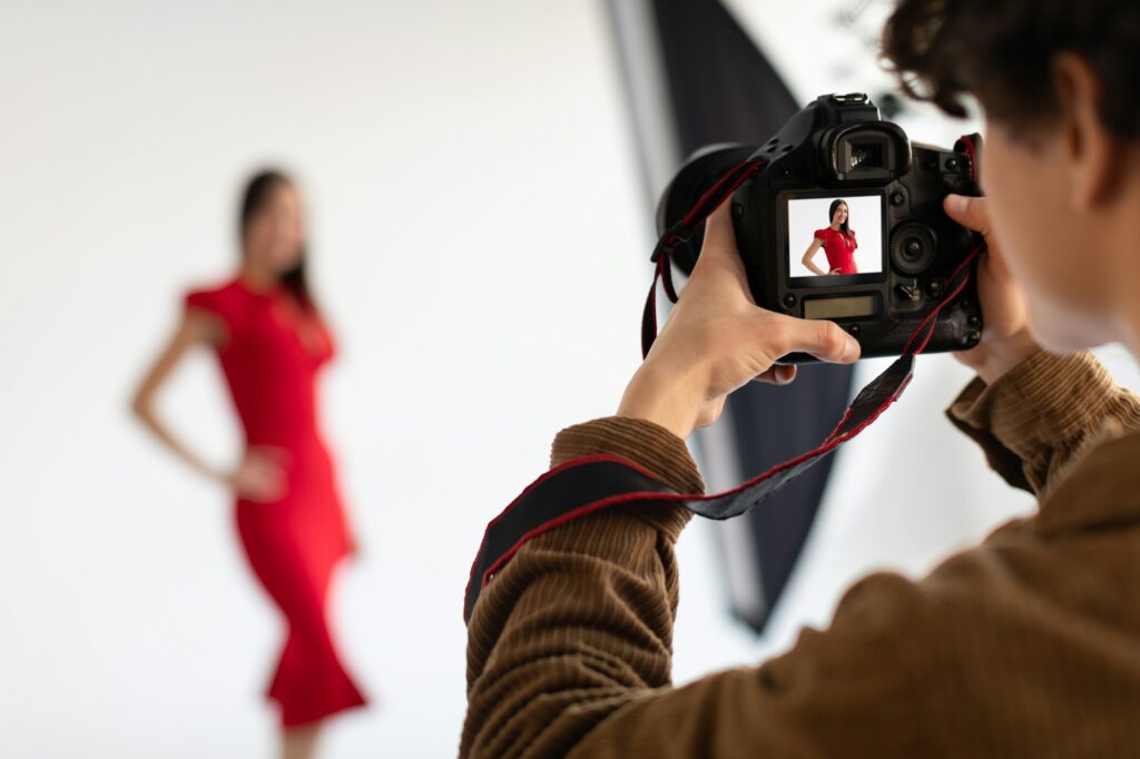 Professional male photographer and beautiful female model in red dress making beauty or content